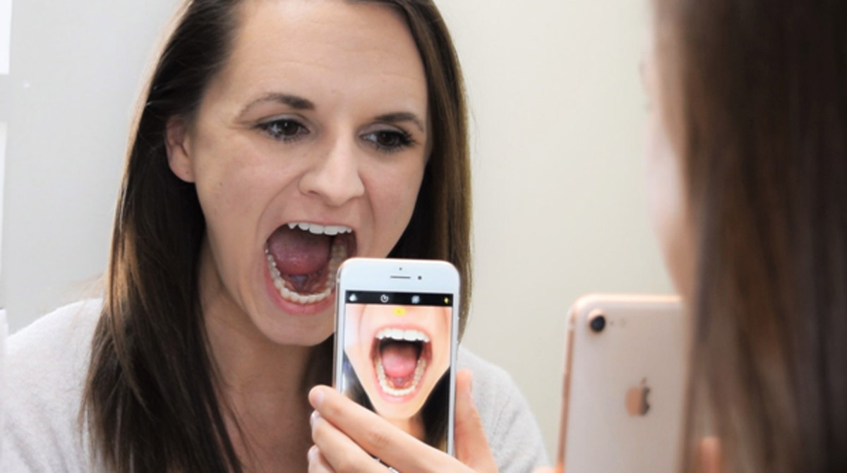 Patient using her phone camera for an evaluation via teledentistry